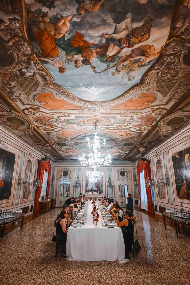 Elegant Venetian banquet hall with ornate ceiling and chandelier lighting.