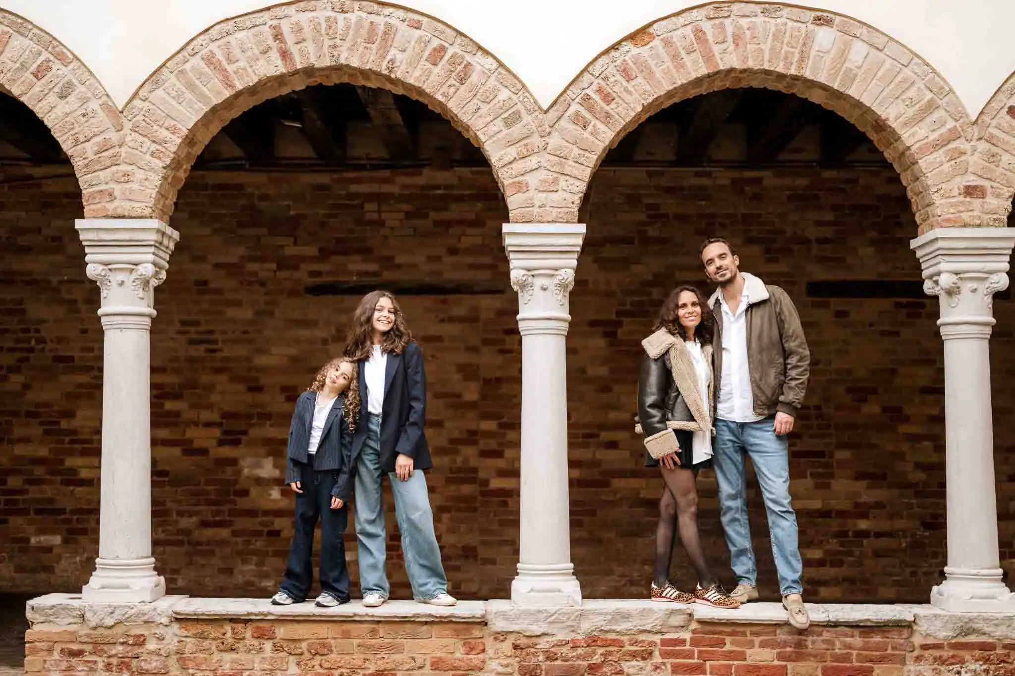Elegant family photo under historic arches in Venice.