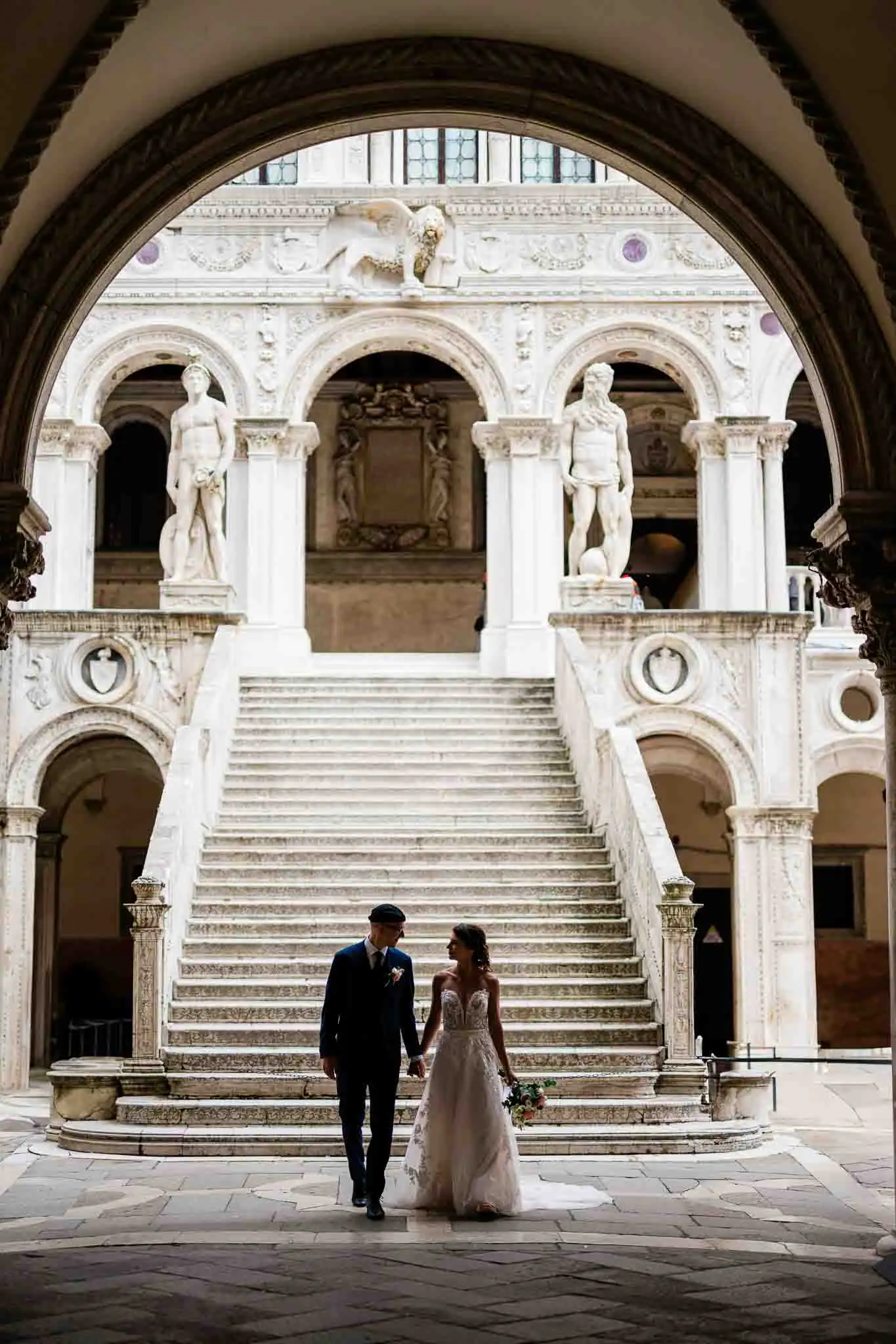 Elegant wedding couple walking in Venice's historic architecture, capturing timeless romance.