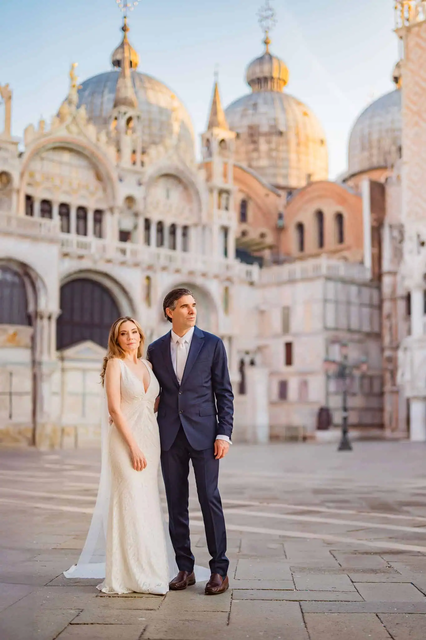 Elegant couple in wedding attire in front of Venice's historic architecture, capturing romantic engagement moments.