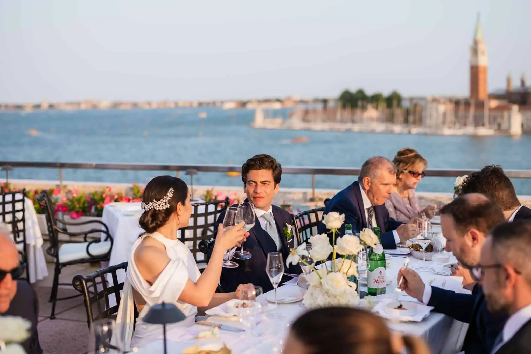 Elegant couple toasting at a Venice wedding reception overlooking the Grand Canal, with historic architecture in the background.