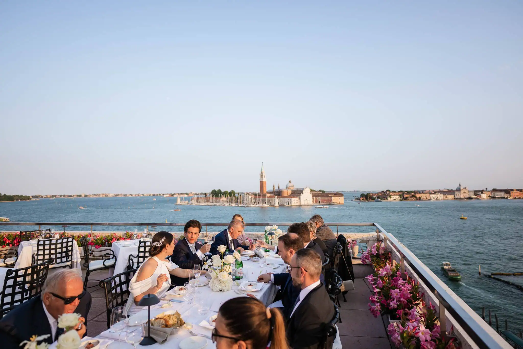 Romantic Venice waterside wedding reception with city skyline view and floral decor.