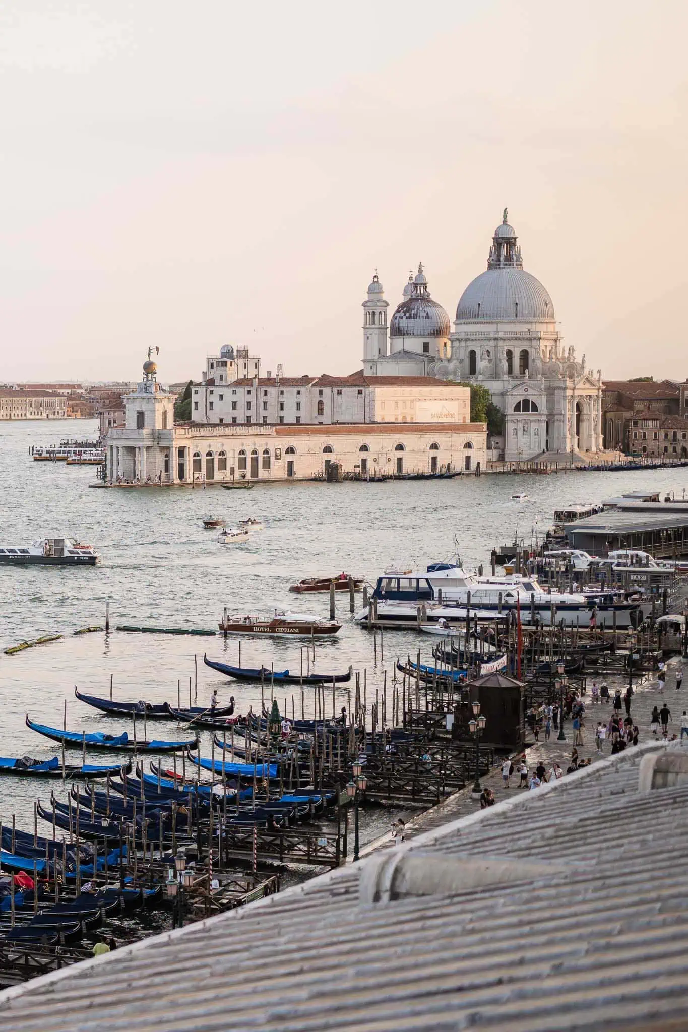 Colorful gondolas docked along Venice's waterfront with the iconic Basilica di Santa Maria della Salute in the background.