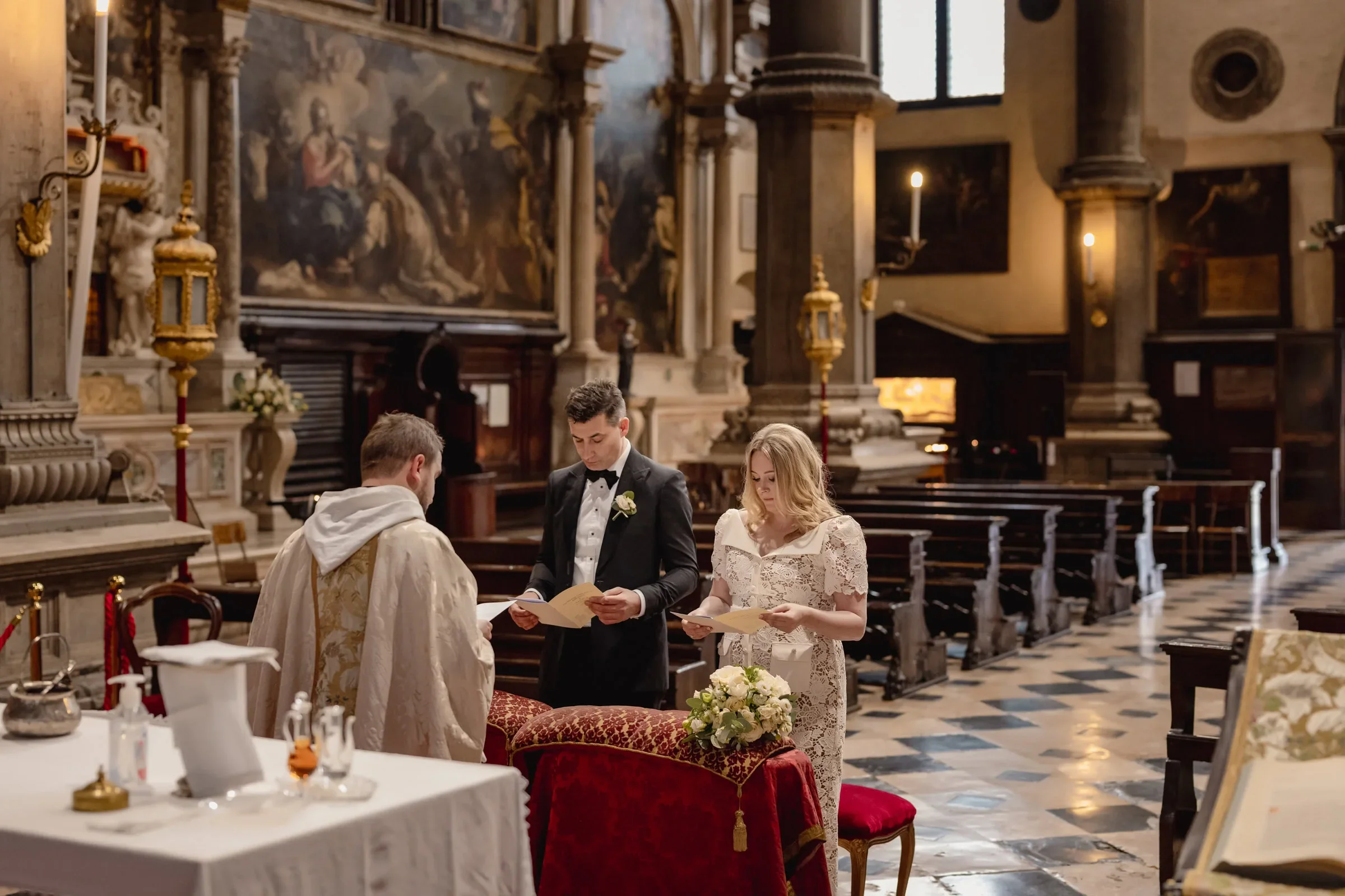 Elegant couple ceremony during a religious wedding inside a historic church with intricate artwork and grand architecture.