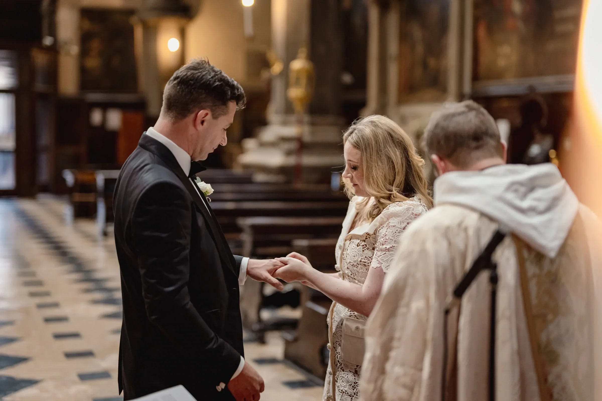 A couple exchanging rings during an intimate wedding ceremony in a historic church.