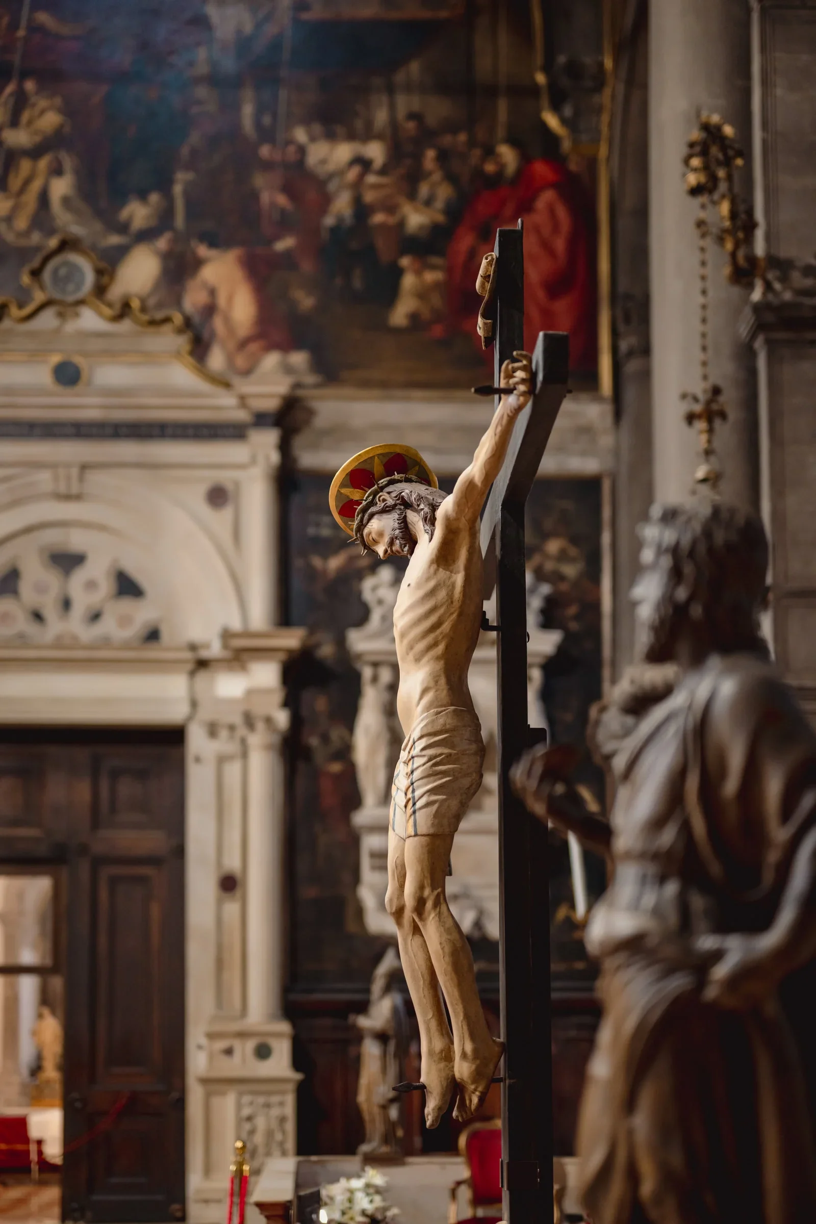 Intricate crucifix sculpture in a historic church with ornate interior and religious artwork.
