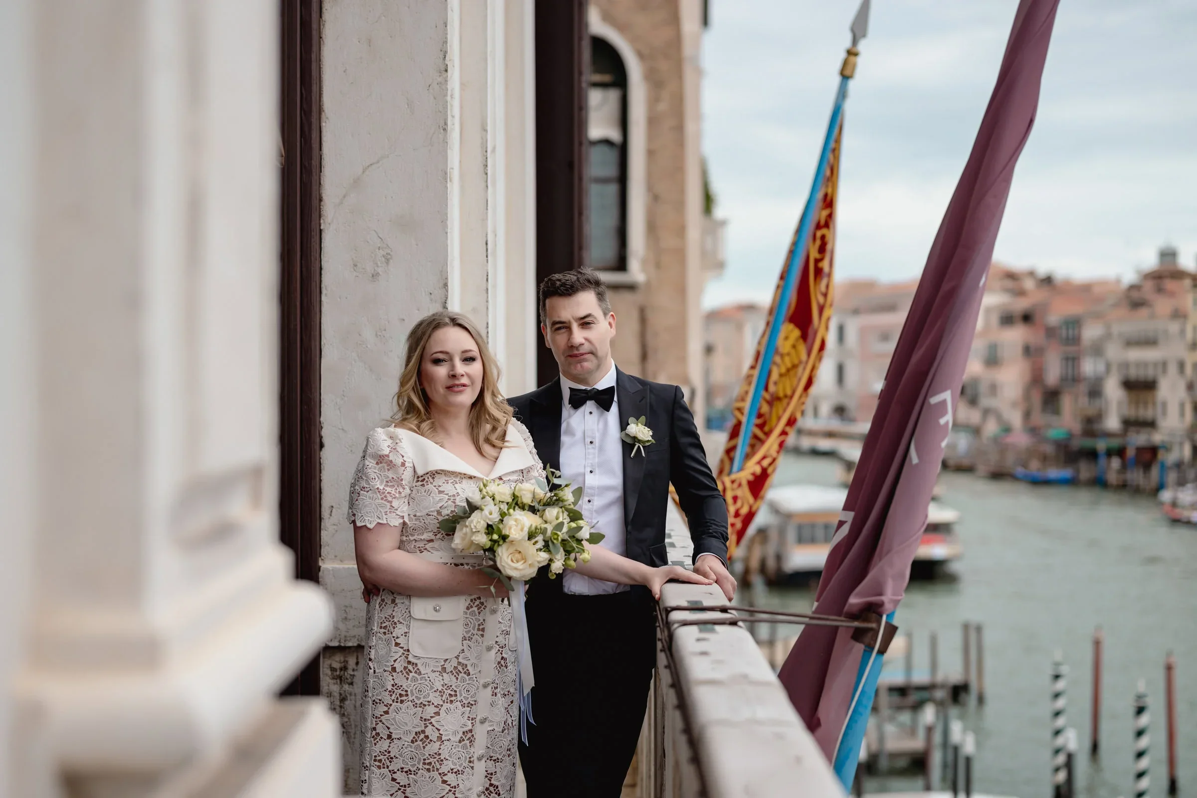 Romantic couple embracing on a balcony in Venice, overlooking canals and historic buildings.