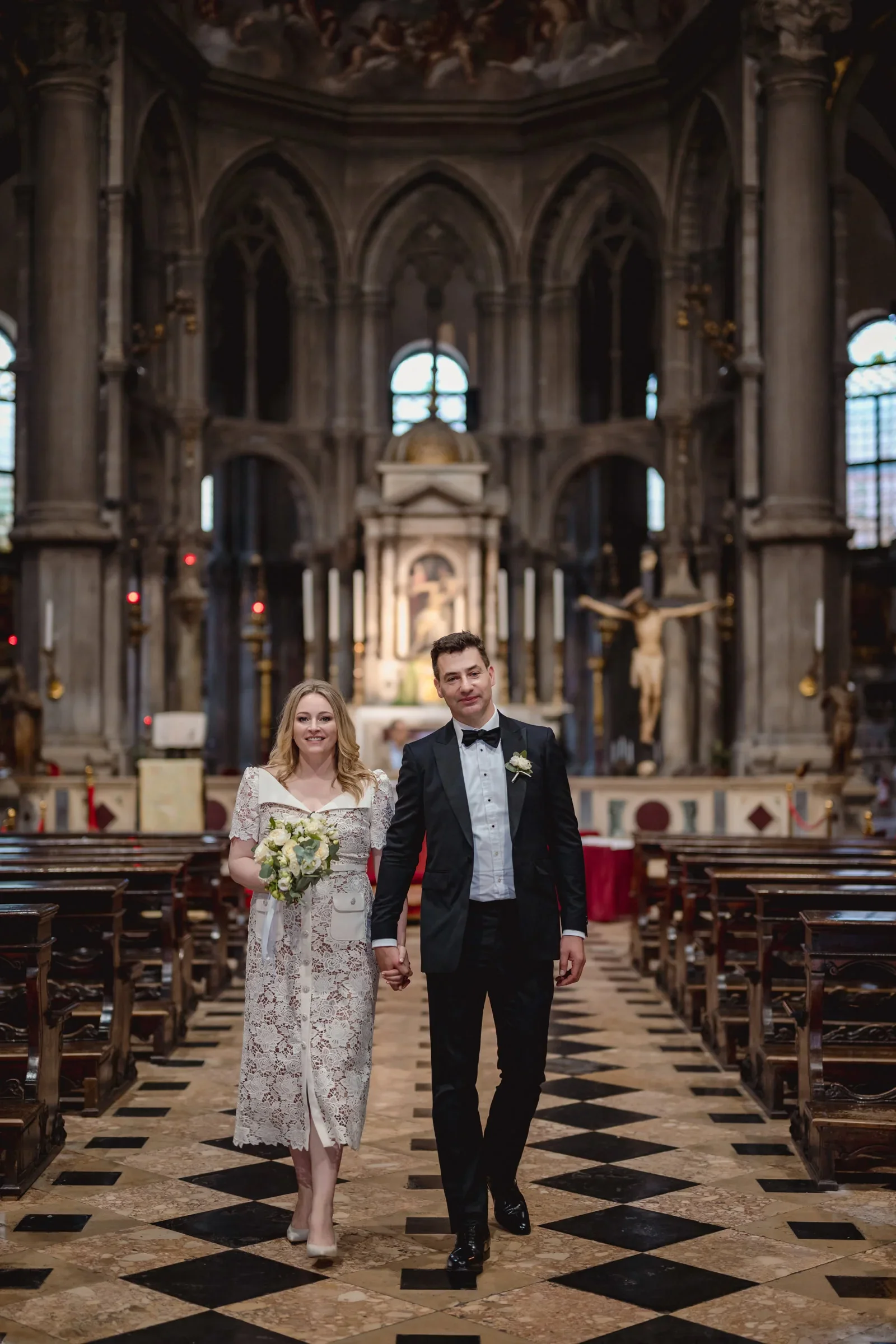 Elegant couple walking hand in hand inside a historic cathedral during their elopement.