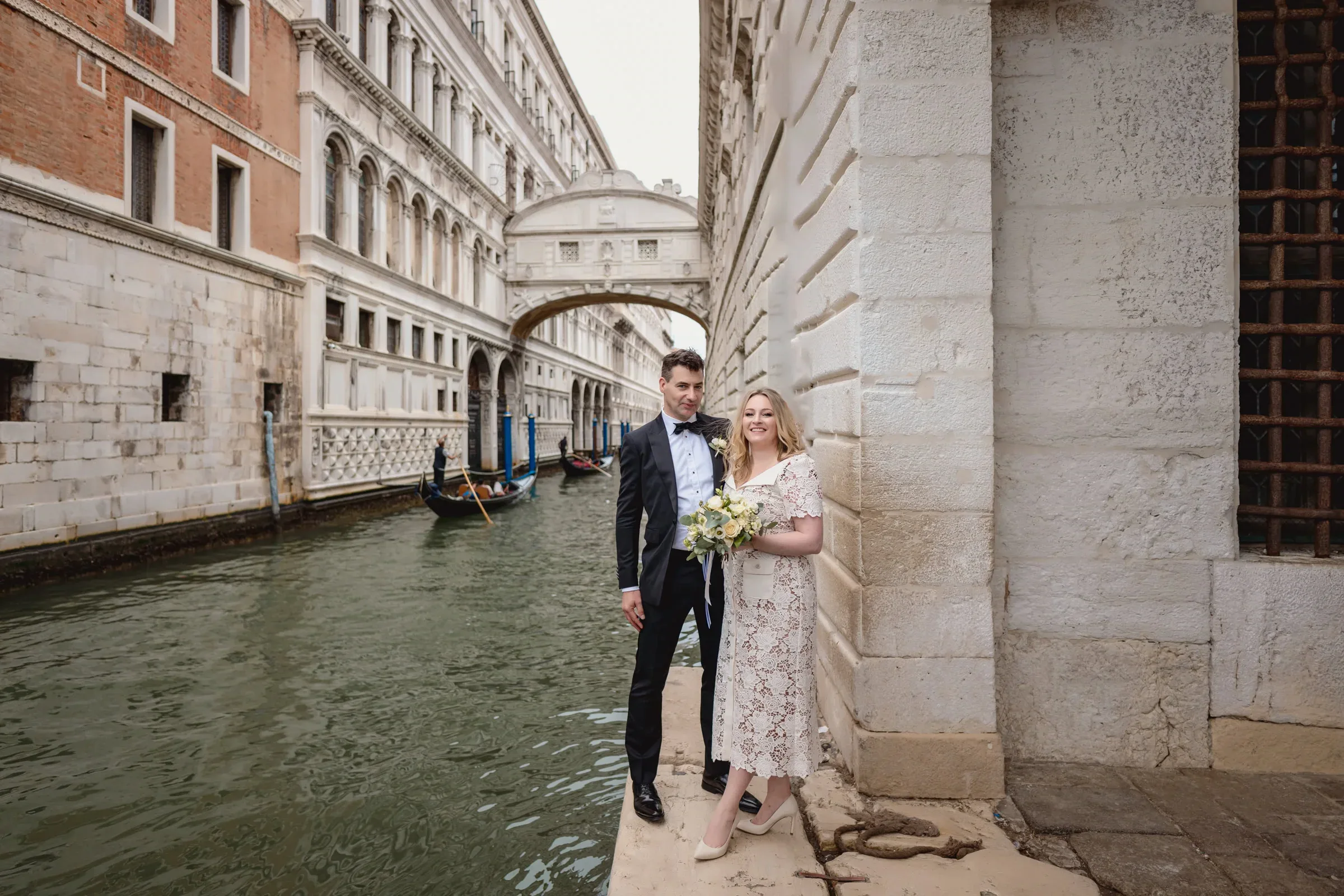 Elegant couple standing by a canal in Venice, Italy.