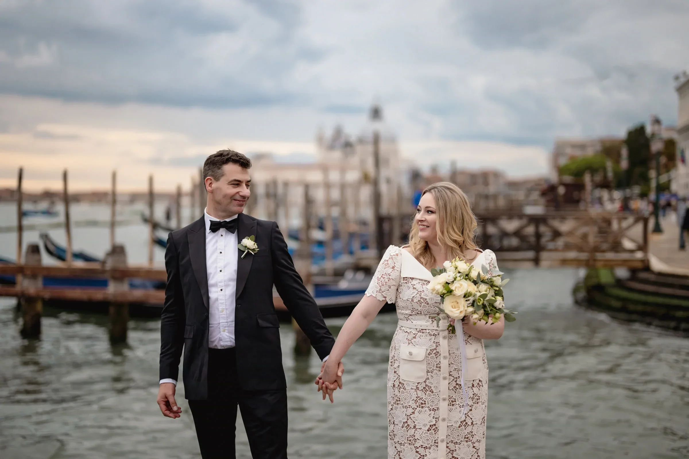 Happy couple holding hands on a boat dock in Venice during their intimate elopement.