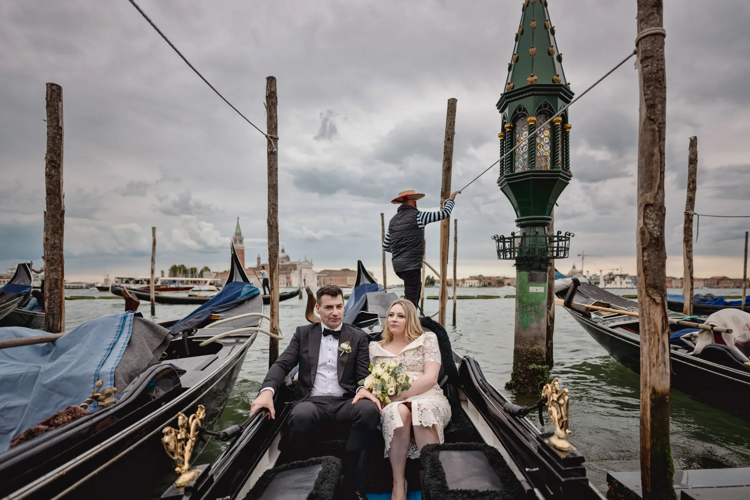 Gondol with a couple in Venice under cloudy skies.