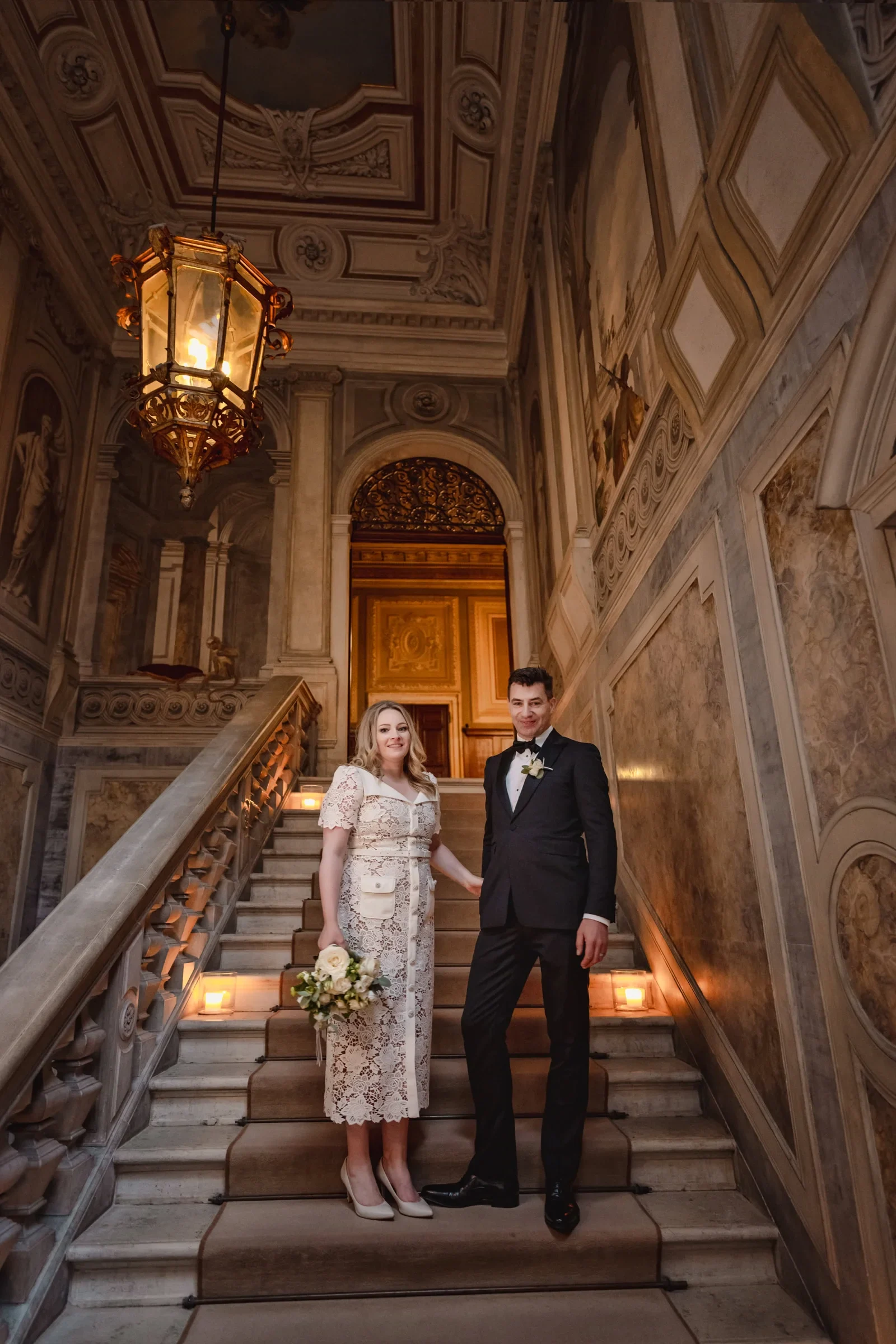 Elegant couple posing on historic staircase during intimate ceremony.