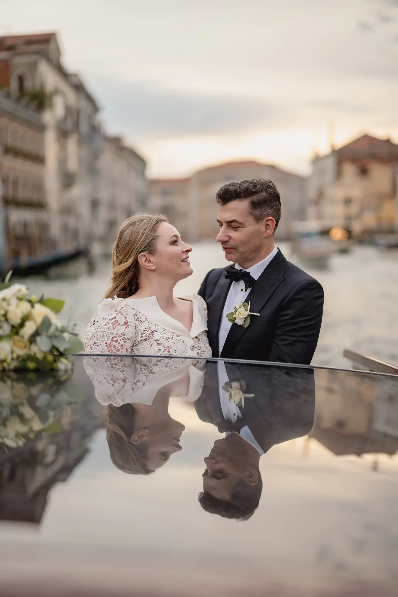 Elegant couple sharing a romantic moment on a gondola in Venice at sunset.