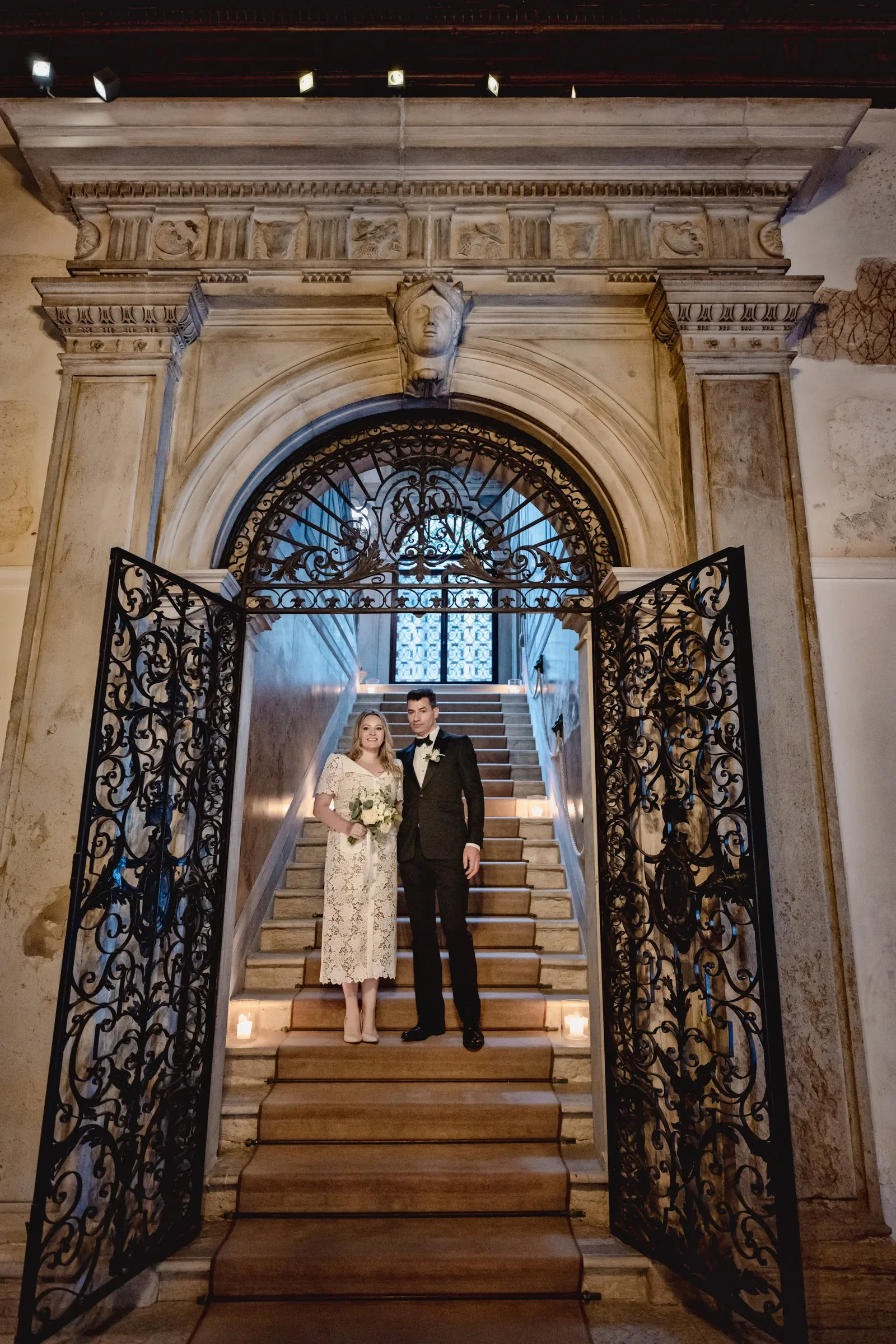 Elegant couple standing on grand staircase in historic building for intimate elopement ceremony.