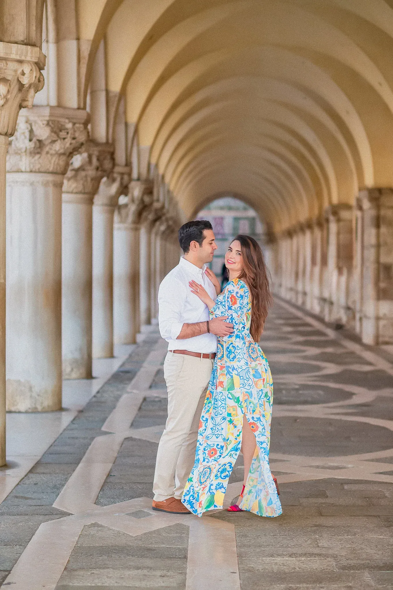 Elegant couple posing during sunset in Venice's historic arches.