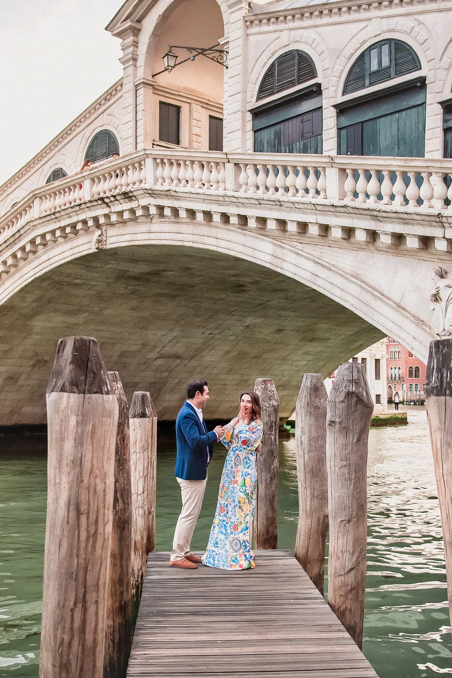Romantic Venice couple proposal under historic bridge, captured by professional photographer.