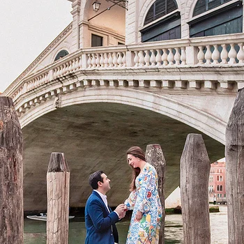 Romantic Venice proposal on a wooden dock by the canal with historic architecture in background.