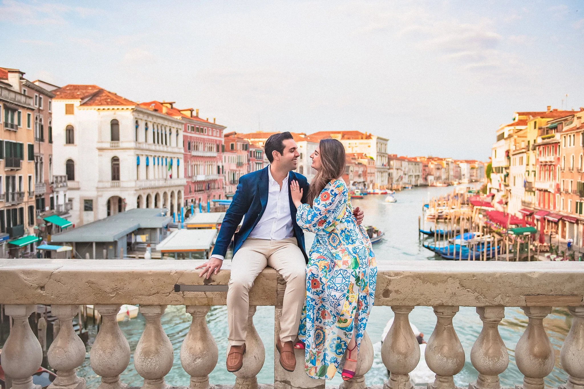 Romantic couple in Venice, on a bridge overlooking the canal during sunset, capturing engagement moments.