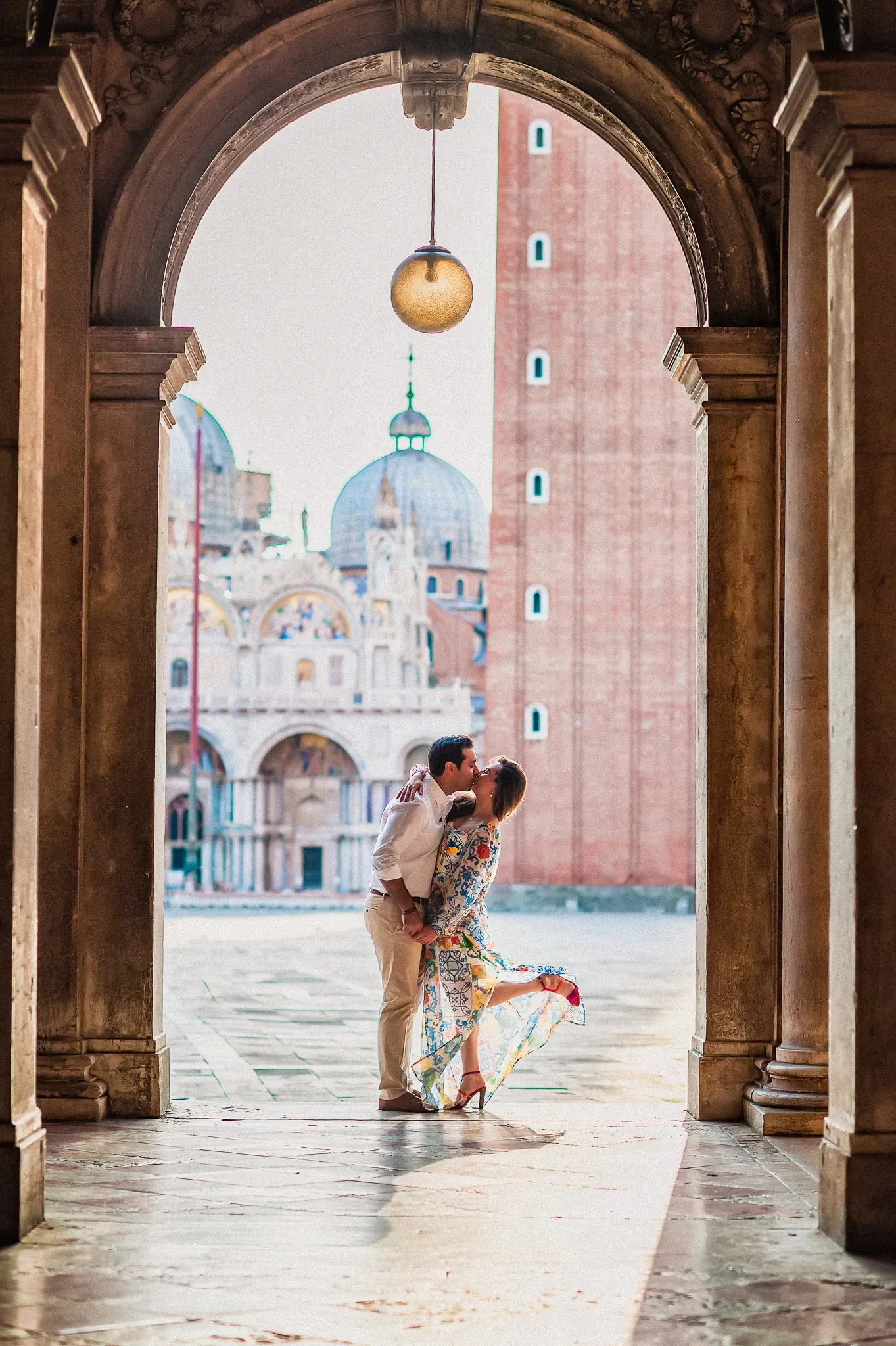 Romantic couple kissing in Venice, historic Basilica in background, engagement photo.