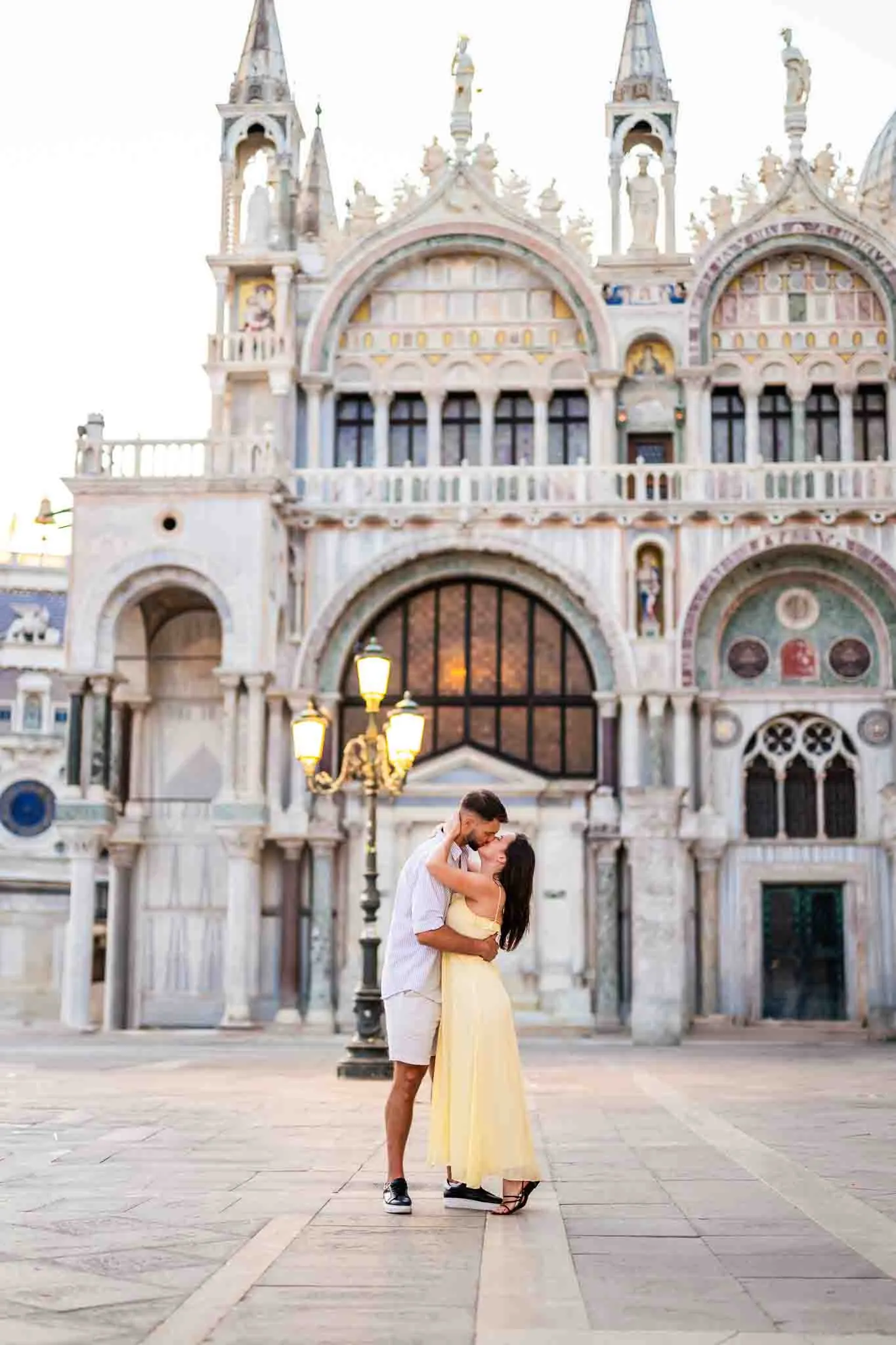 Romantic couple embracing in Venice with historic architecture in the background.