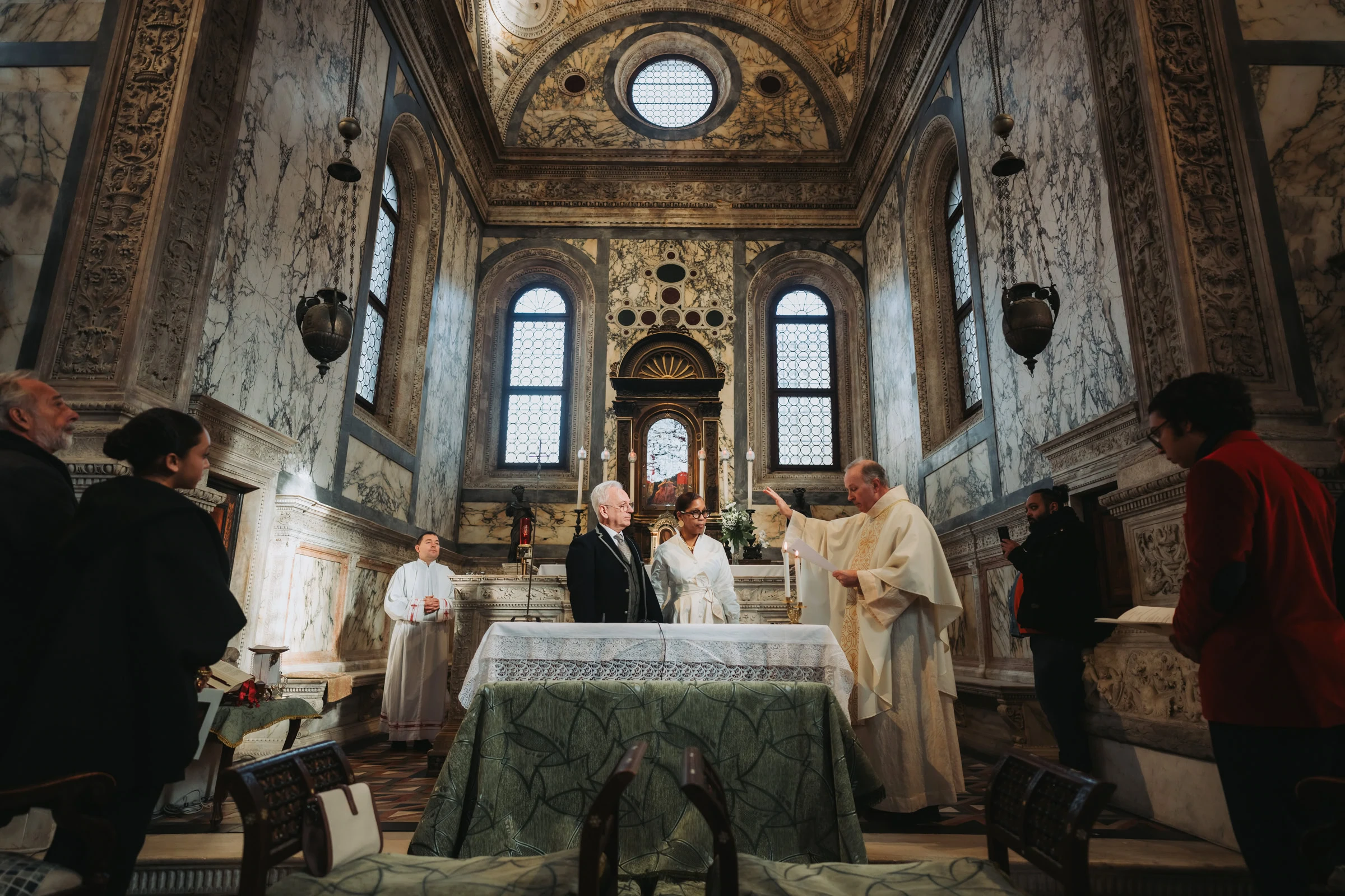 Elegant Venice wedding ceremony in a historic marble church with clergy, couple, and guests.