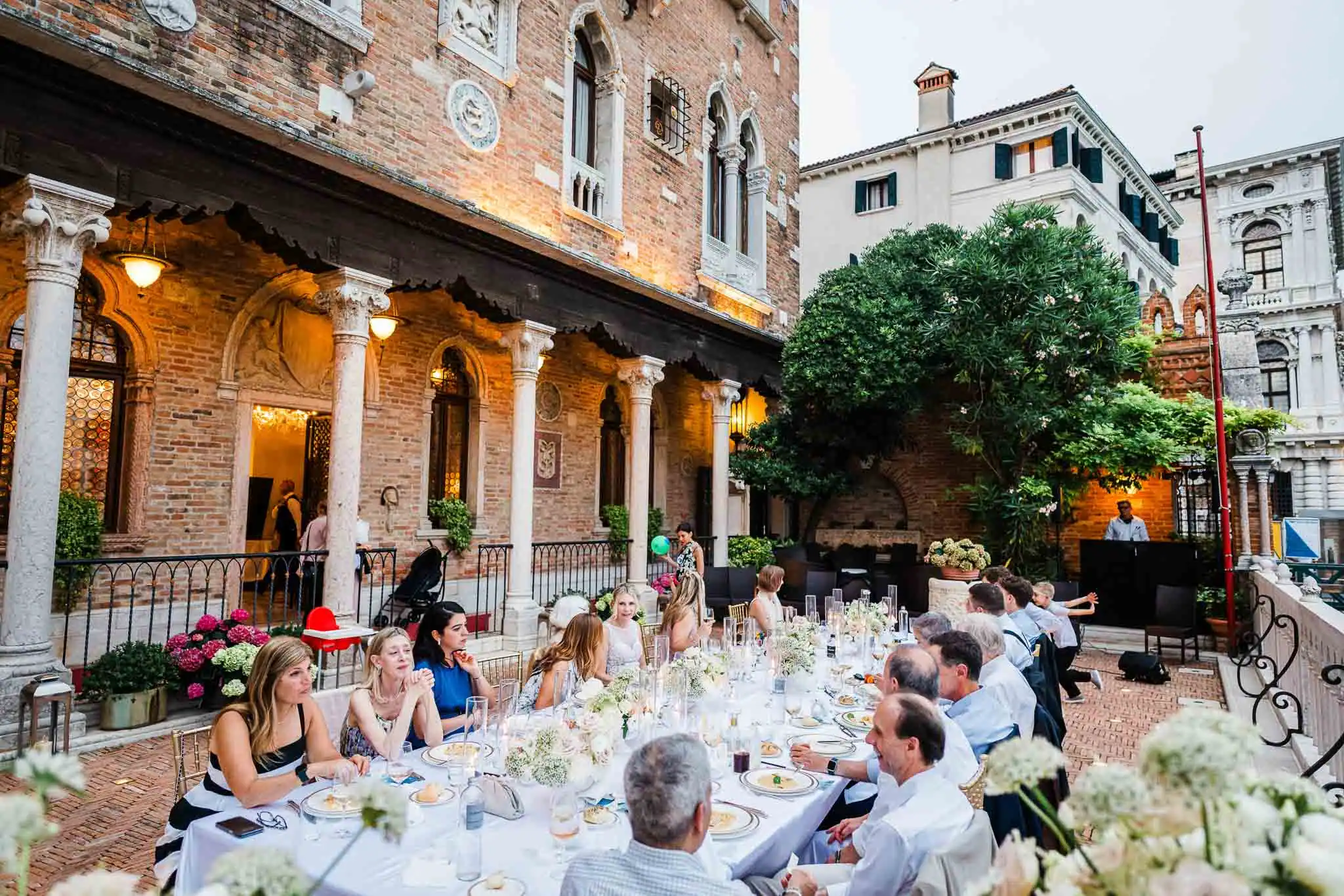 Elegant Venice wedding reception outdoor in historic courtyard with guests dining and celebrating.