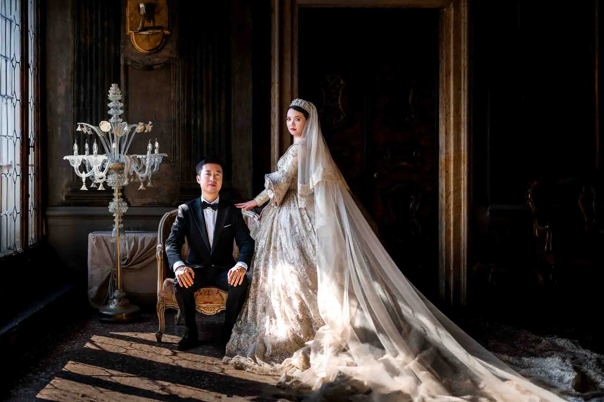 Elegant Venetian wedding couple in luxurious attire inside a historic mansion.