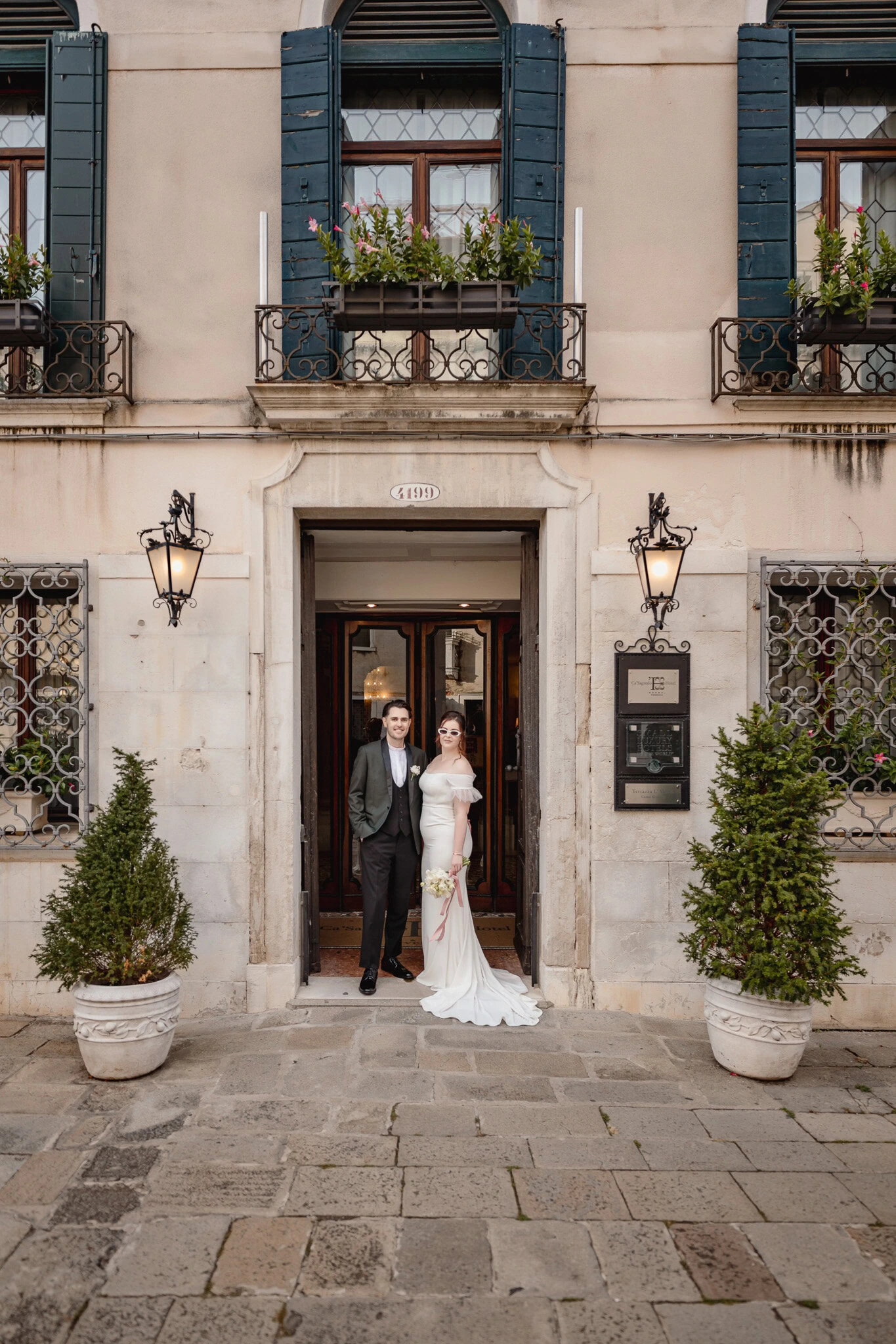 A couple standing at the entrance of Ca’ Sagredo Palace in Venice.