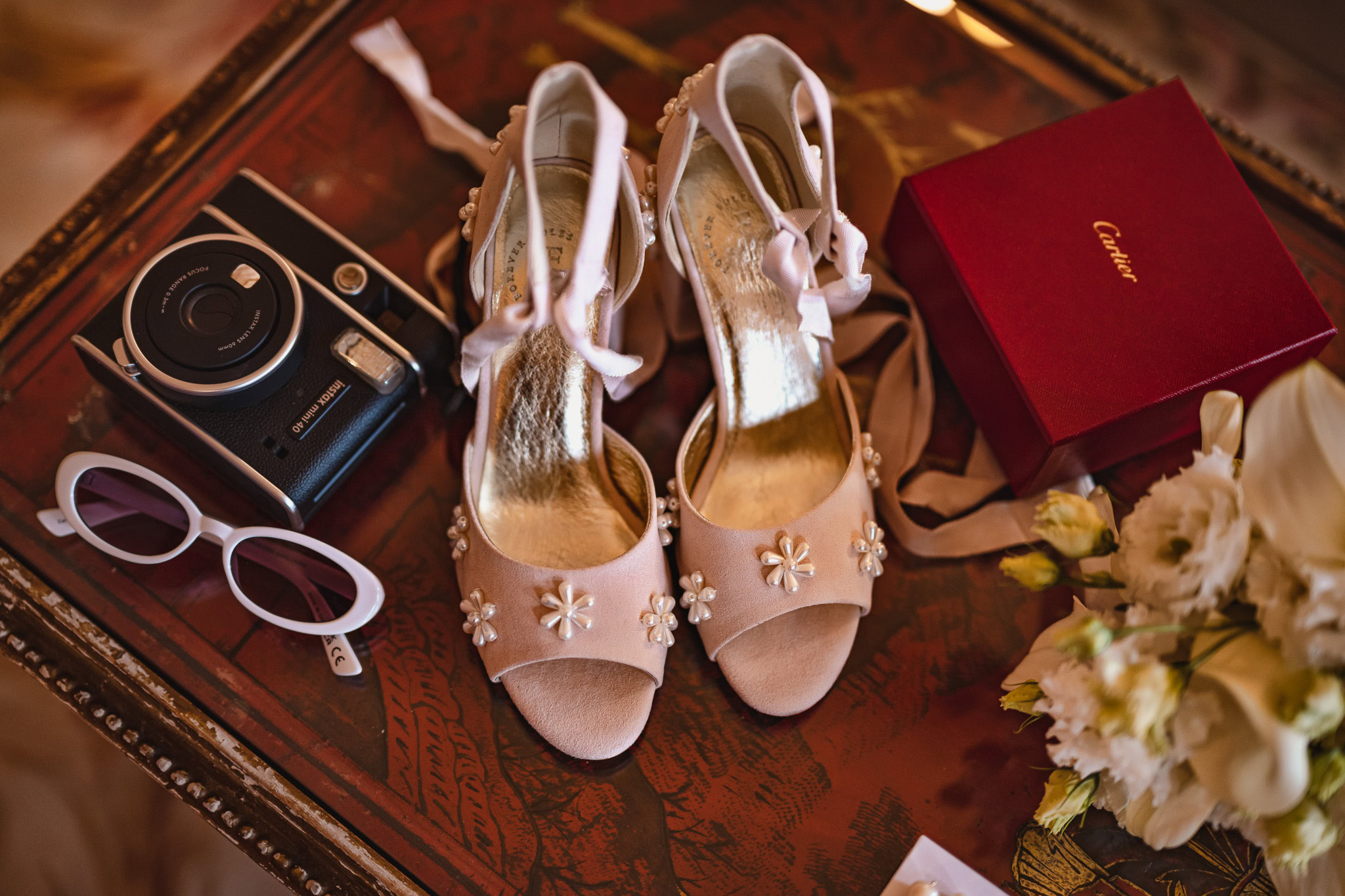 Elegant shoes, camera, and accessories on a wooden table at Ca’ Sagredo Palace.
