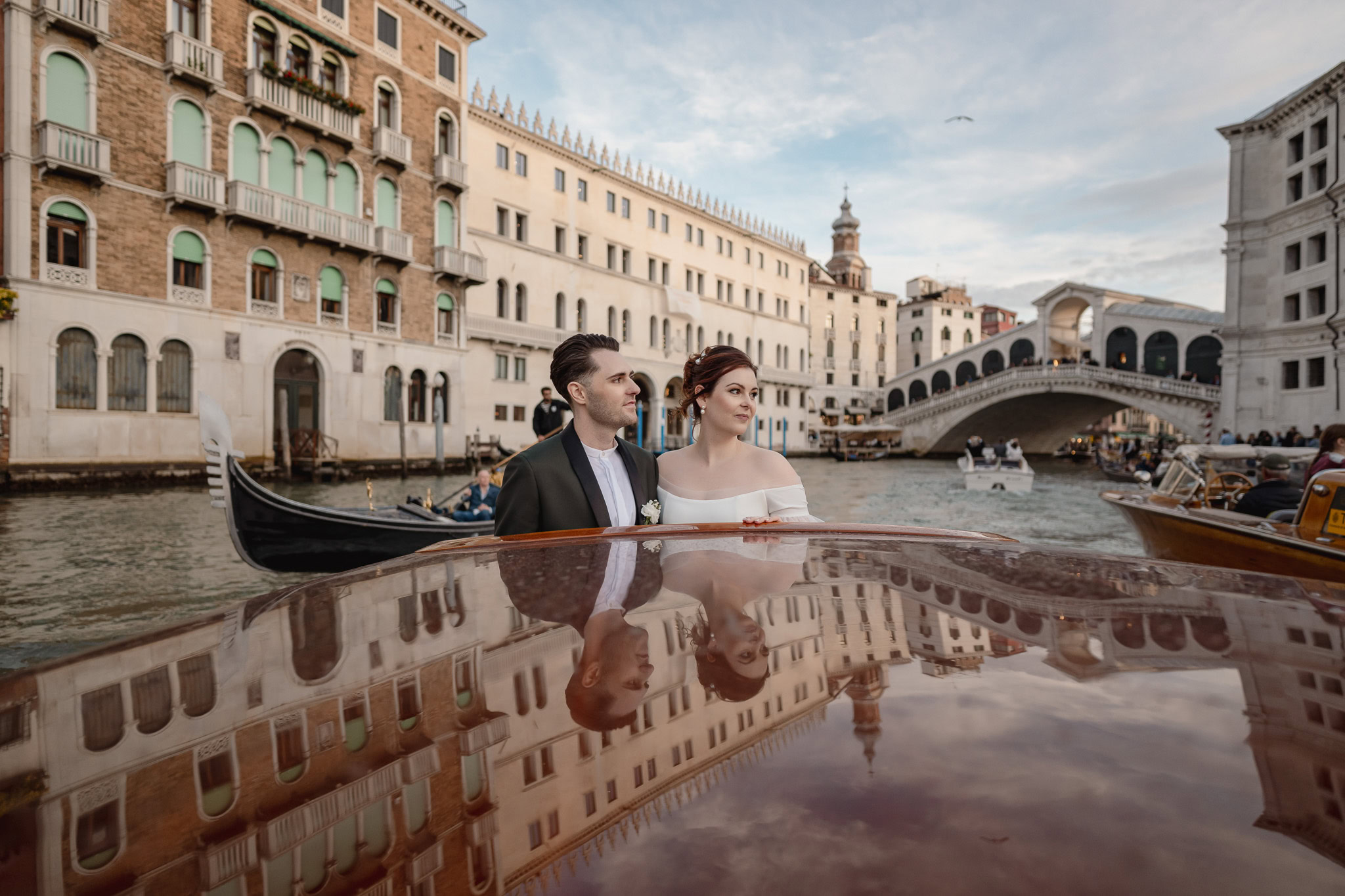 Couple in formal attire on a boat near Ca’ Sagredo Palace in Venice.