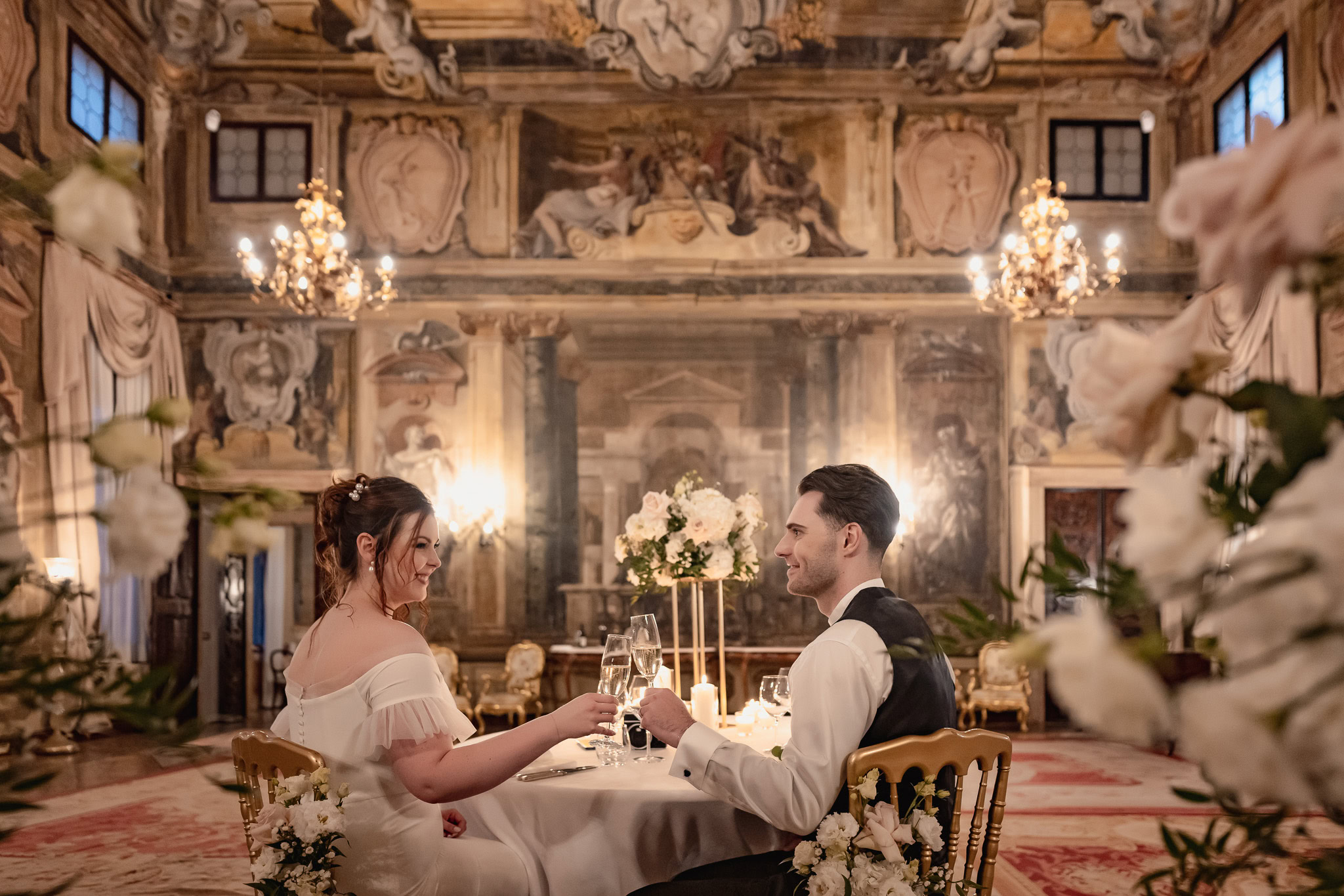Elegant couple seated at a table inside Ca’ Sagredo Palace in Venice during an elopement.