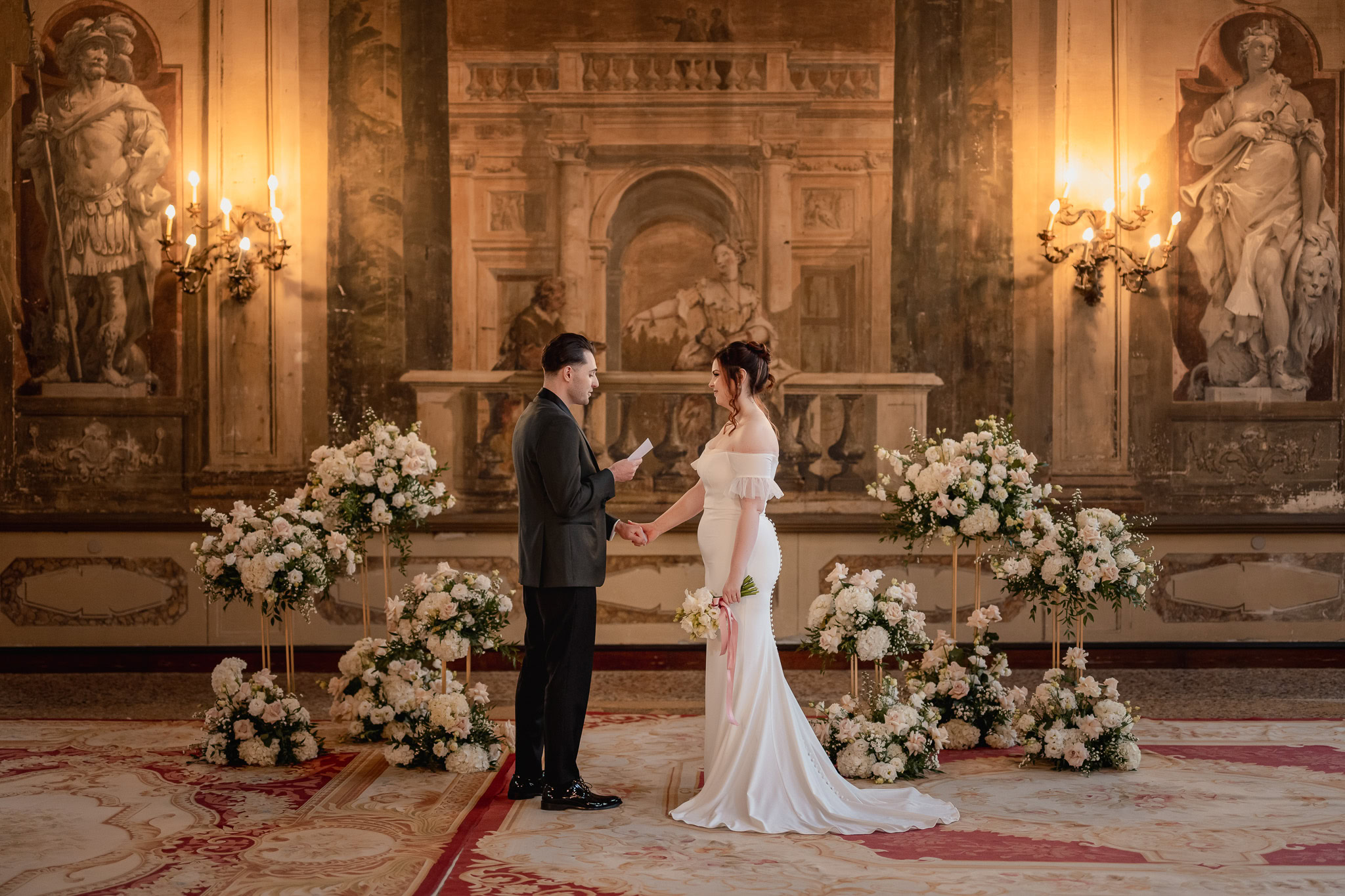 A couple holding hands during an elopement ceremony at Ca’ Sagredo Palace in Venice.