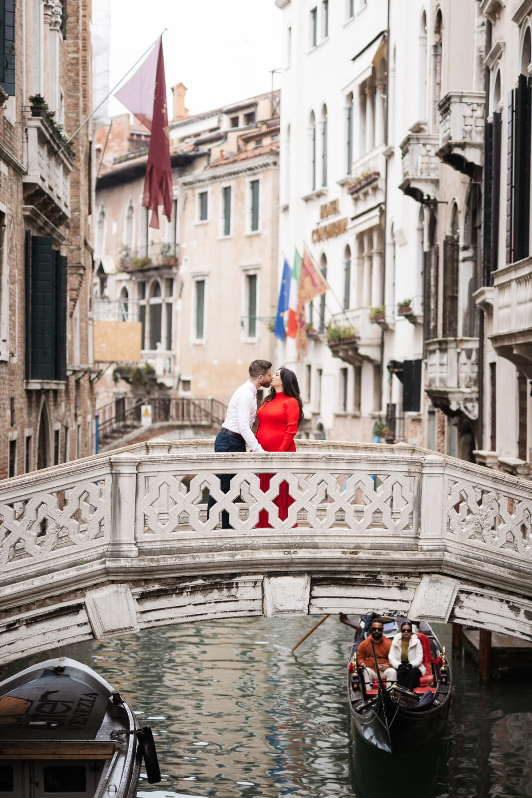 A couple sharing a romantic moment on a small bridge over Venice's canals during their babymoon.
