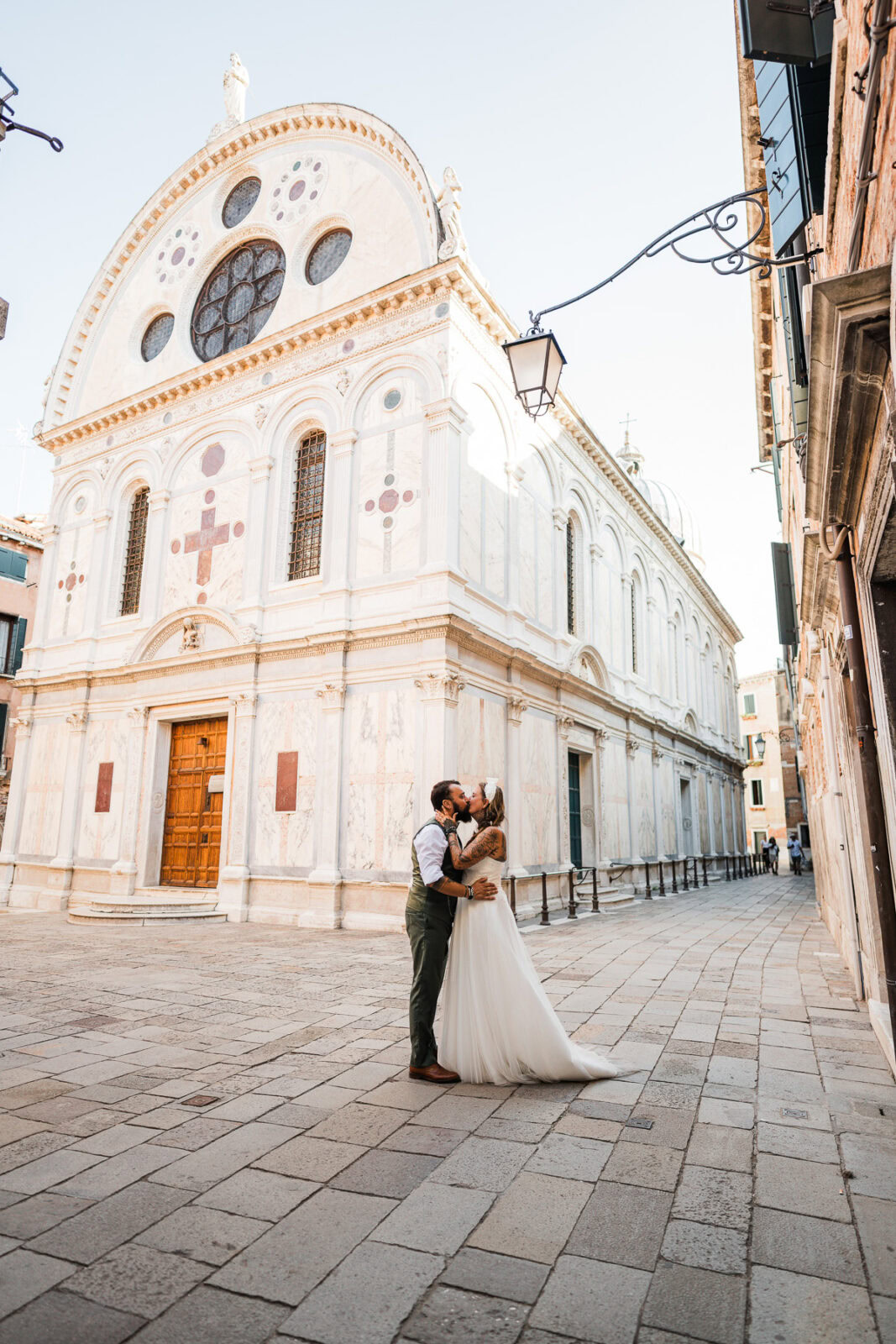 Romantic couple embracing in front of a historic Venetian church at dawn.