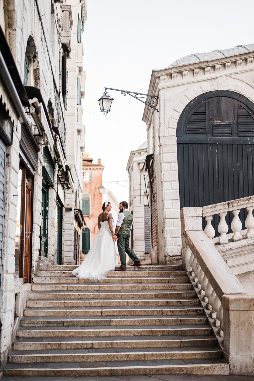 Romantic couple holding hands on Venice stairs during early morning, quiet and intimate at.