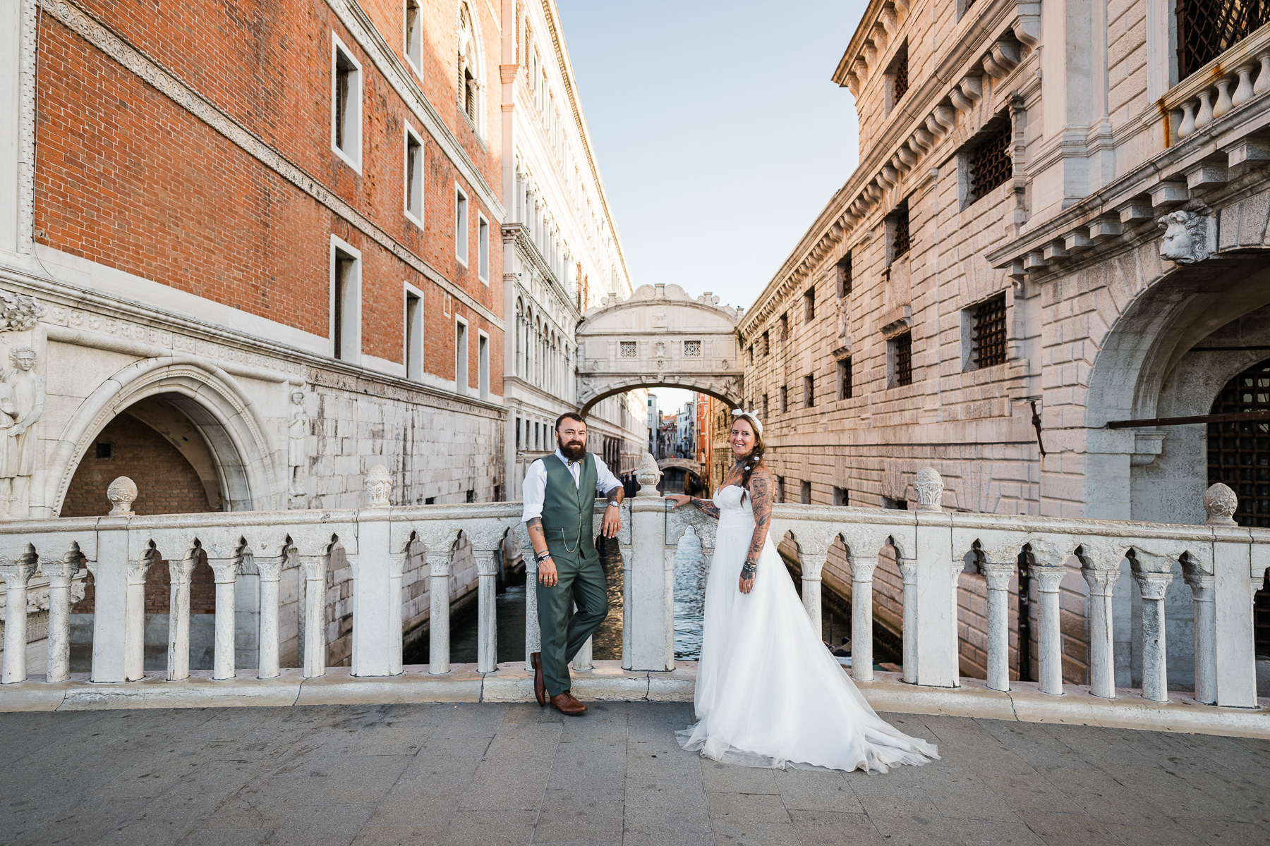 Romantic newlyweds walking along Venice canal bridge at dawn, soft light and quiet atmosph.