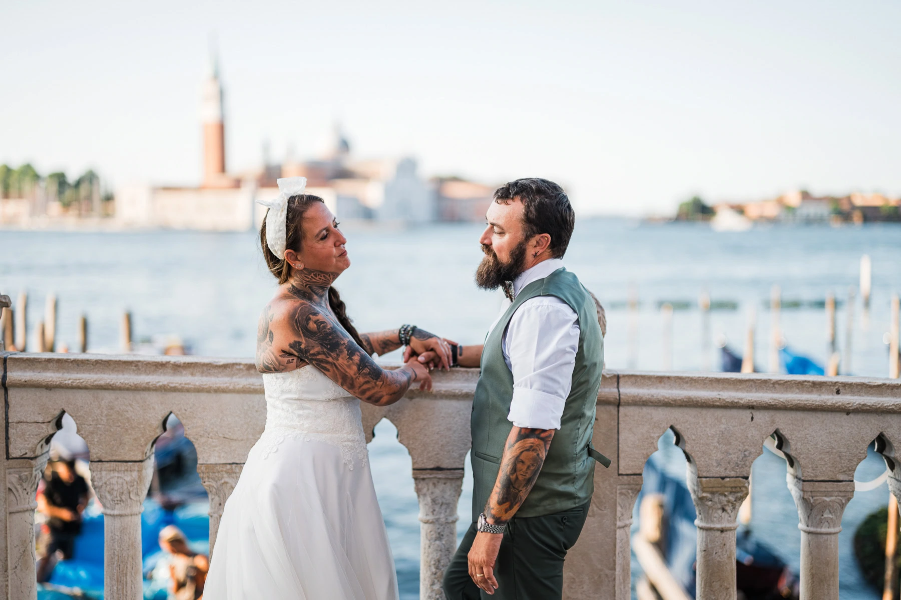 Couple holding hands by Venice canal with historic buildings in the background.