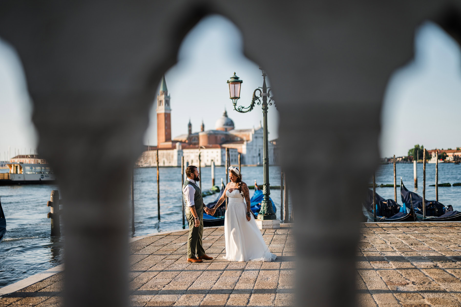 Romantic couple holding hands by Venice canal at dawn, early morning light and quiet atmos.