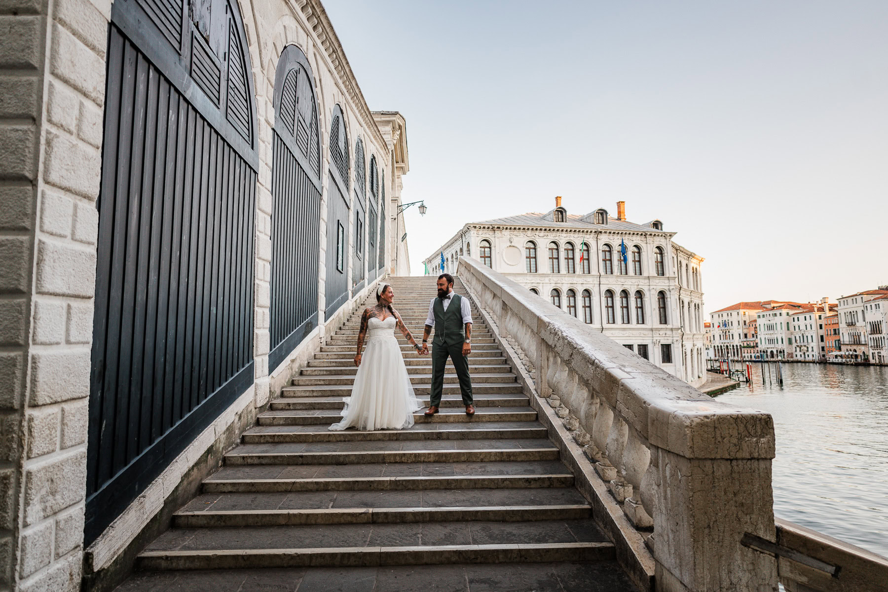 Romantic couple walking on Venice bridge during early morning, soft light and peaceful atm.