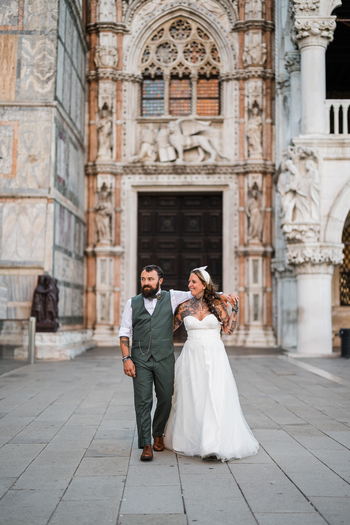 Couple walking hand-in-hand in front of historic Venice cathedral at dawn.