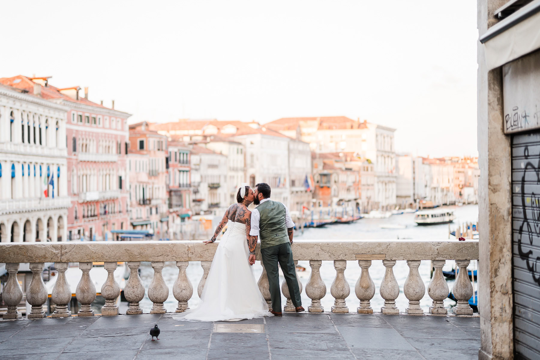Romantic couple walking along Venice canal at dawn, early morning light and quiet atmosphe.