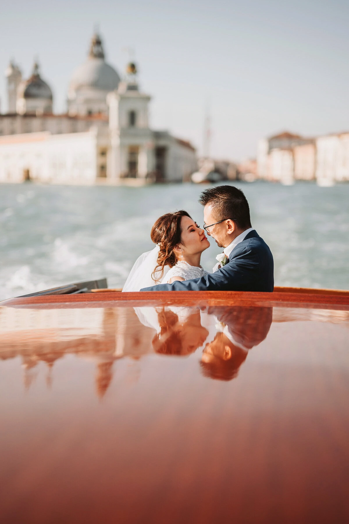 Couple embracing on a boat with Venice's Scuola Grande dei Carmini in the background.