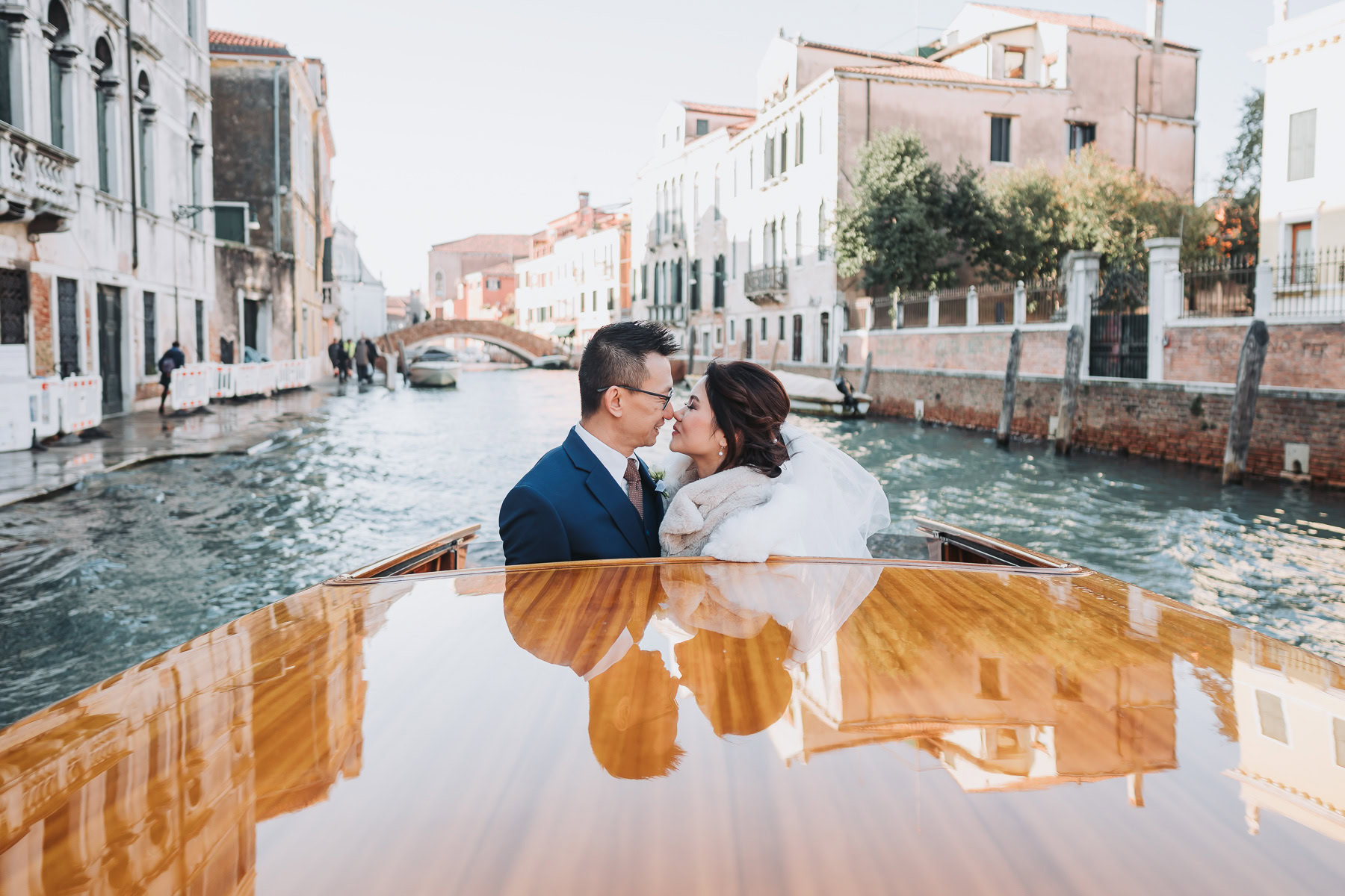 A couple sharing a tender moment on a boat in Venice near Scuola Grande dei Carmini.