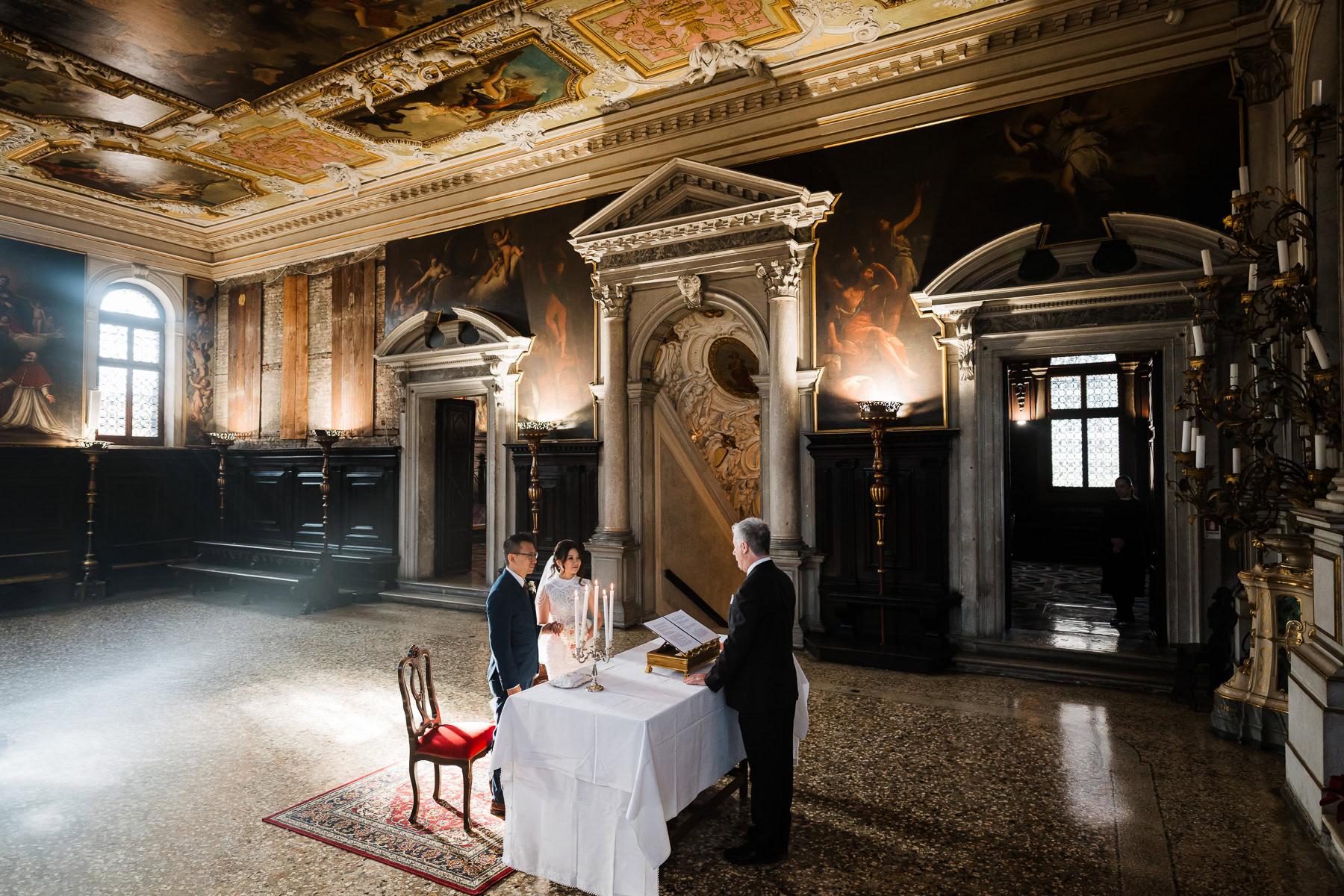Interior of Scuola Grande dei Carmini with a couple and officiant during an elopement cere.