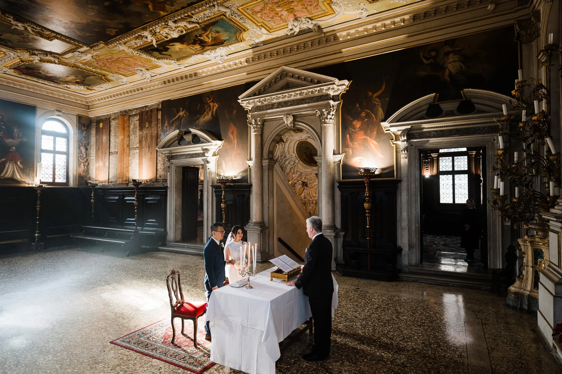 Interior of Scuola Grande dei Carmini with a couple and officiant during an elopement cere.