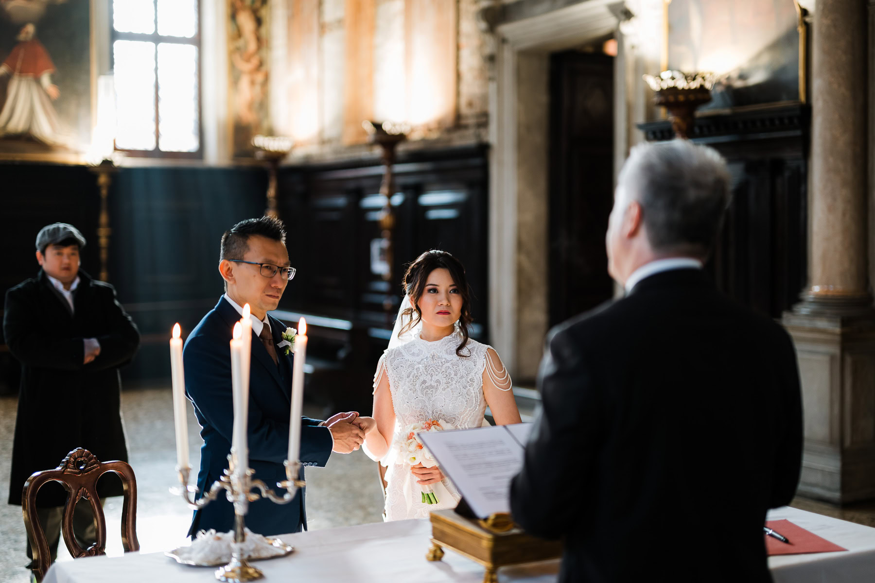 Couple standing at altar inside Scuola Grande dei Carmini in Venice during elopement cerem.