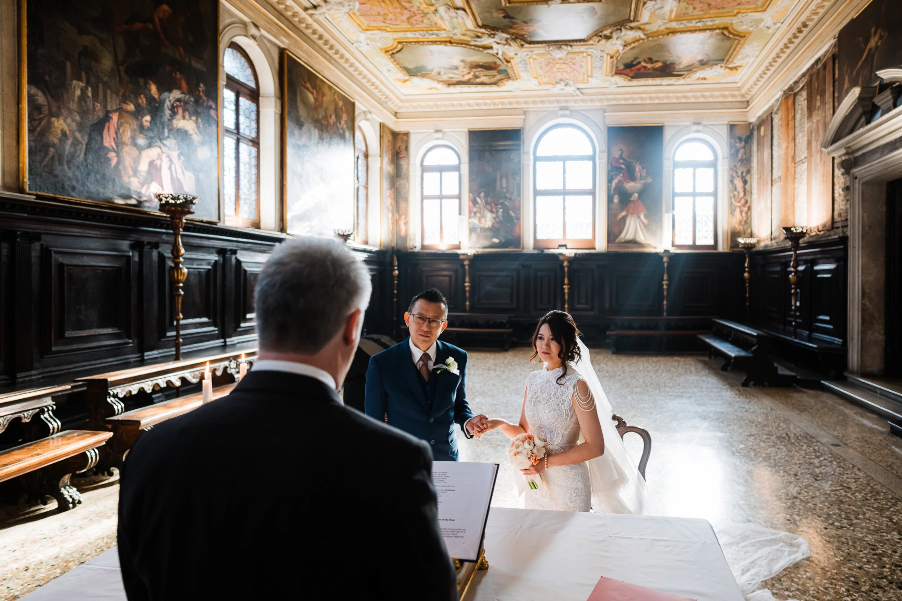 Couple holding hands during elopement ceremony at Scuola Grande dei Carmini in Venice.