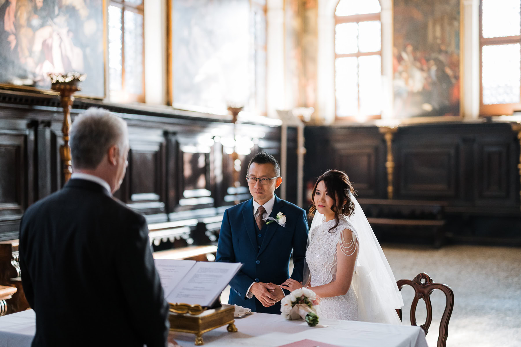 Couple standing at an altar inside Scuola Grande dei Carmini in Venice.