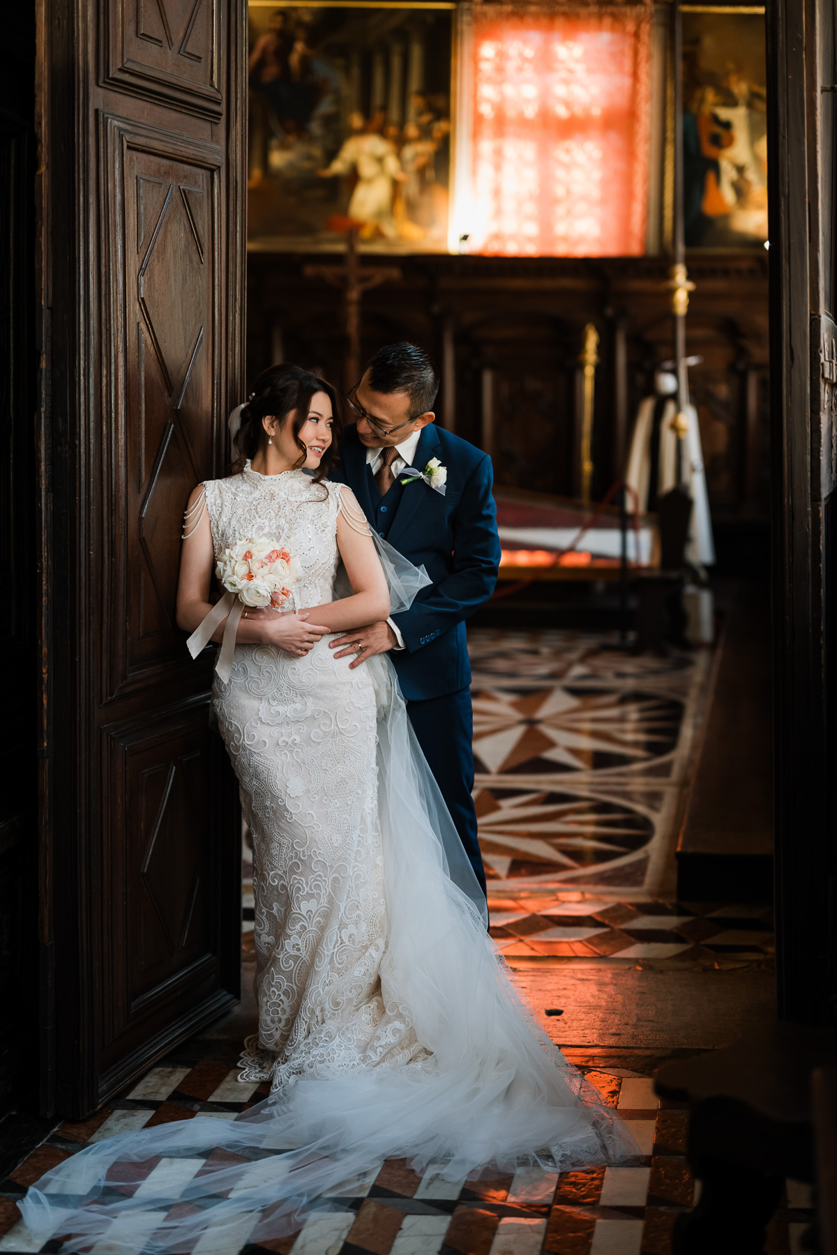 Couple standing inside Scuola Grande dei Carmini, Venice, in elegant attire.