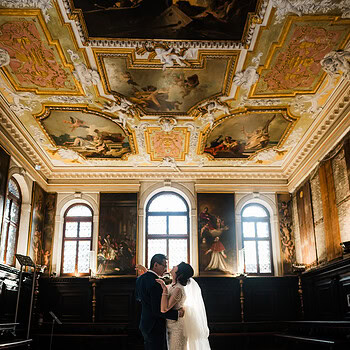 A couple standing close together inside the ornate Scuola Grande dei Carmini with elaborat.